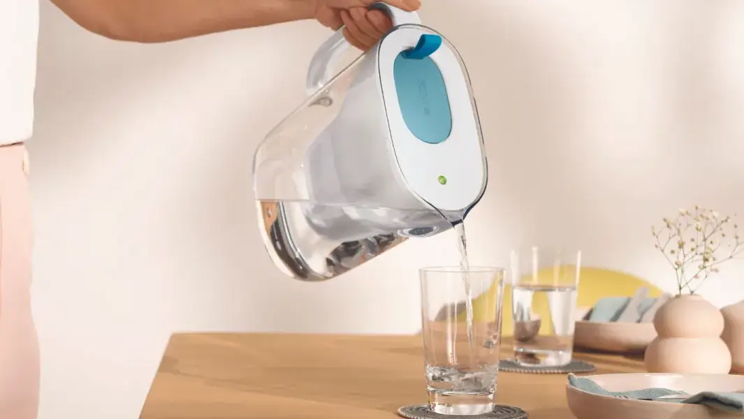 Carafe filtrante BRITA versant de l'eau dans un verre sur une table de cuisine