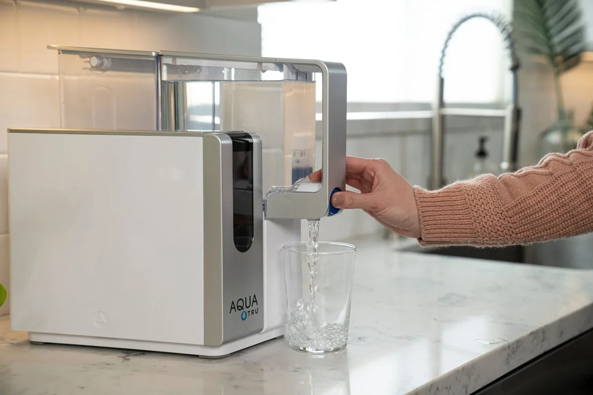 Osmoseur de comptoir AquaTru Classic remplissant un verre d'eau filtrée sur un plan de travail